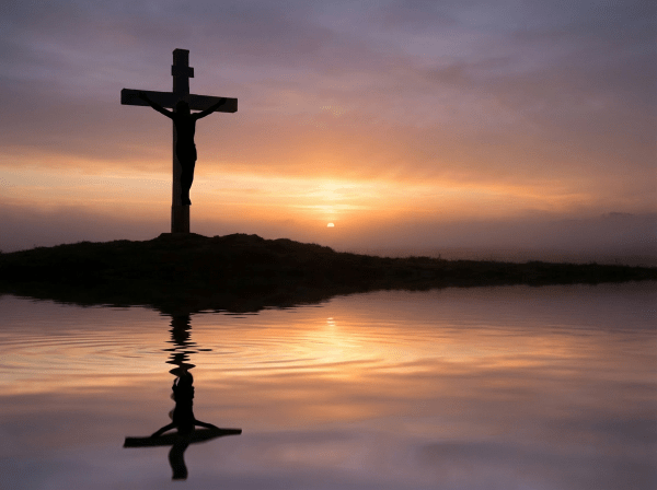Silhouette of a cross at sunrise over water with text Good Friday Reflection.